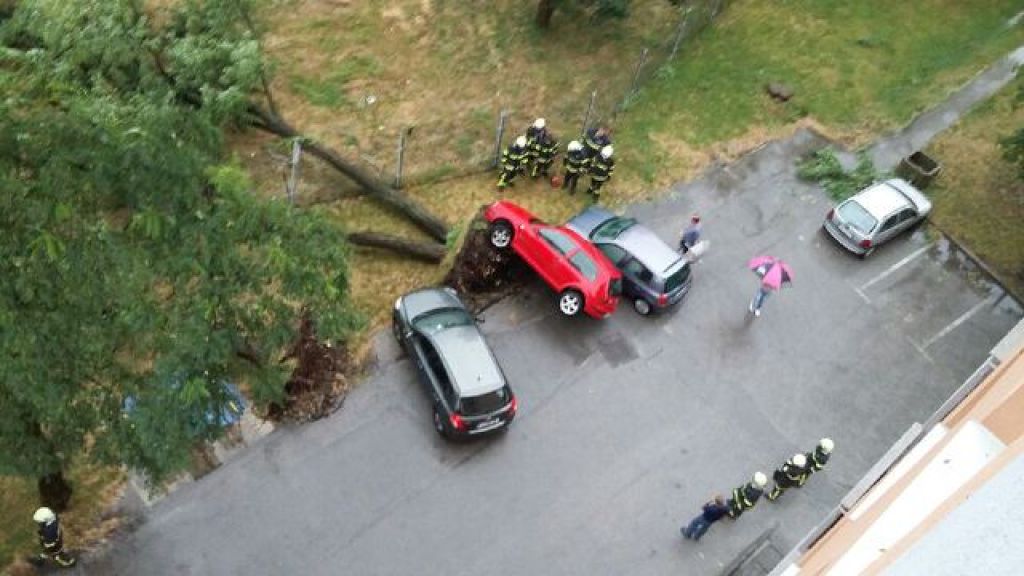 FOTO: Drevo se je zrušilo in dvignilo avto, veter odtrgal obrobo strehe